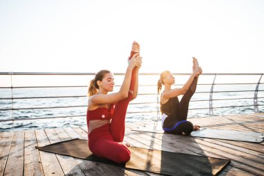 Sabahın köründe sahilde yoga yapan genç kadınlar.
