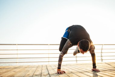 Yoga yaparken vinç pozu veren genç bir adam. 