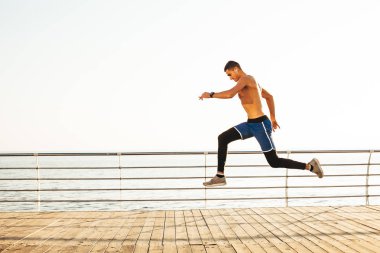 Sportif adam denizin arka planına karşı havada sıçrıyor.