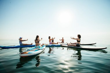Gün doğumunda gölde pilates yapan genç bir kadın.