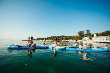 Gün doğumunda gölde pilates yapan genç bir kadın.