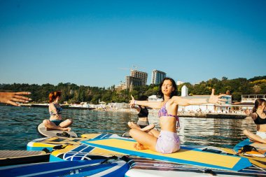 Gün doğumunda gölde pilates yapan genç bir kadın.