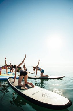 Gün doğumunda gölde pilates yapan genç bir kadın.