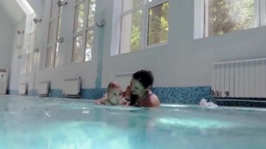 Bebek, kadının yardımıyla suyun altında yüzüyor.