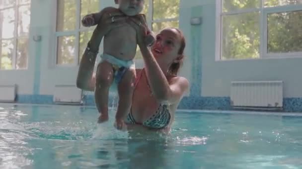 家人和他可爱的孩子在游泳池里游泳 快乐的家庭在游泳池里玩得开心 — 图库视频影像