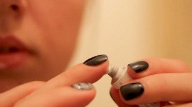 Bir kadın dilinde ülser üzerinde iyileştirici bir merhem bir parmak ile geçerlidir. Herpes.