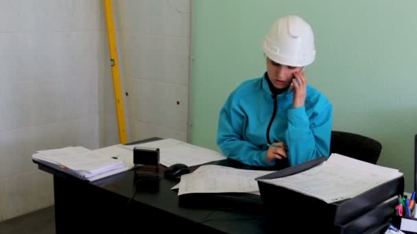 Ingenieur builder is het bestuderen van blauwdrukken met behulp van een telefoon — Stockvideo