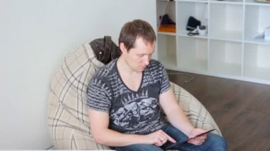 Genç çekici adam evde oturan tablet kullanır