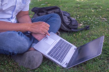Bir kişi kendi dizüstü kullanarak ve bazı işlerini bir çim veya Bahçe.