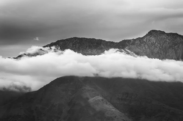 Nubes Blancas Colgantes Bajas Frente Una Montaña Con Cielo Oscuro Fotos de stock libres de derechos