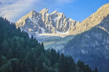 Sunrise bir karla kaplı dağ tepe üzerinde. Bir buzul ve Olimpiyatlar yarın başlıyor ön planda bir çam ormanı ile bir dağ