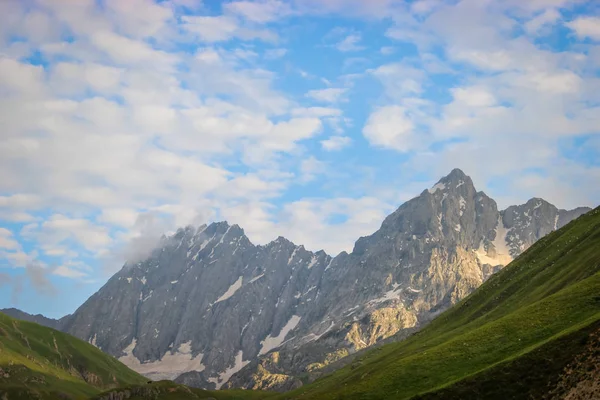 Low clouds, Stratus clouds just above the towering Himalayan mountains in Kashmir with deep blue skies. Sunrise on mountains in Himalayas.