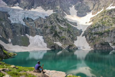 Gadsar, Keşmir, Hindistan- Tarih- Mayıs 18, 2019: Gadsar Gölü turkuaz yeşil su bakan bir kişi yürüyüşçü trekker. Gadsar Gölü Keşmir'deki Great Lakes Trek'in bir parçasıdır.