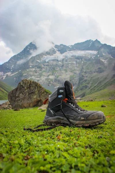 Sonmarg, Jammu e Caxemira, Índia: Date- 20 de maio de 2019: Quechua sapatos de caminhada de um caminhante na grama verde durante uma caminhada com montanhas no fundo — Fotografia de Stock
