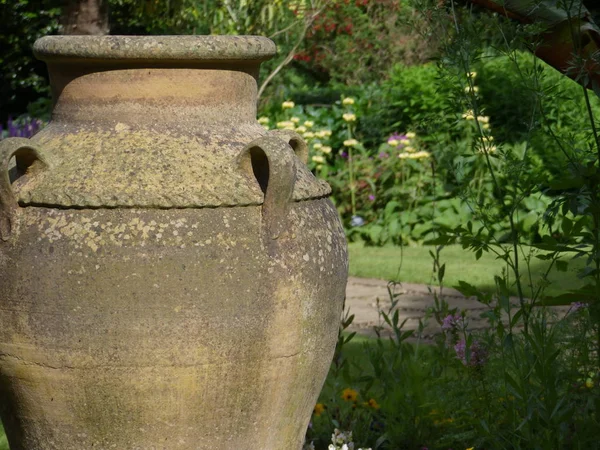 A large ornamental garden planter or vase set in gardens as a feature