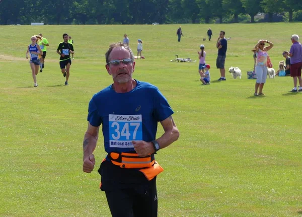 Silsoe, Inglaterra - 24 de junio de 2018 - Un corredor de mediana edad está llegando a la meta después de una agotadora carrera de 5 km en el evento anual Silsoe Stride — Foto de Stock