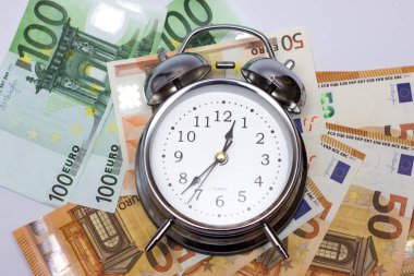 Bir çalar saat ve beyaz zemin üzerine Avrupa kağıt para. İş kavramı, vakit nakittir.