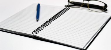 Defter ve gözlük ve kırmızı kalem masada. Beyaz arka plan