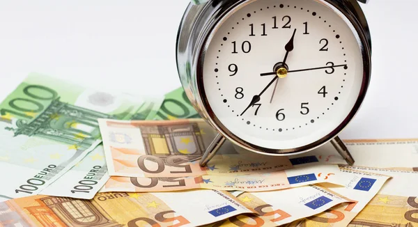 Bir çalar saat ve beyaz zemin üzerine Avrupa kağıt para. İş kavramı, vakit nakittir.
