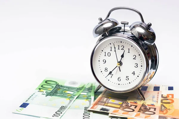 目覚まし時計や白い背景の上のヨーロッパの紙幣 ビジネス コンセプトは 時は金なり ストックフォト