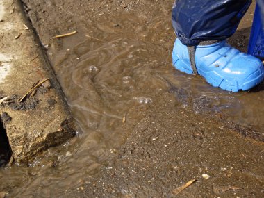 çocuk ilkbaharda kauçuk botlar su birikintileri ile yürür, Mosco