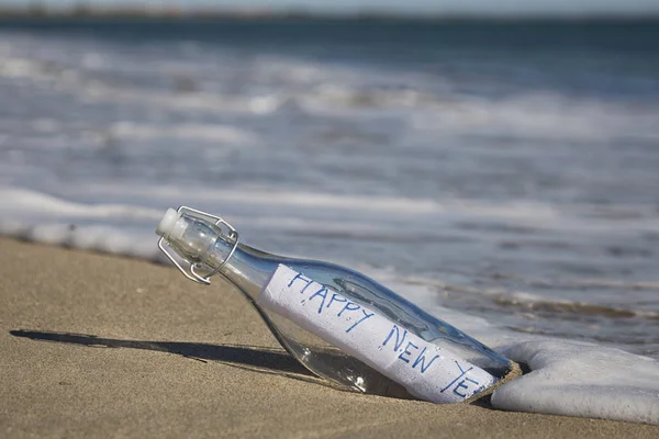 A Happy New Year Message in a bottle at the beach.