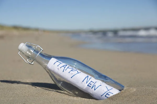 A Happy New Year Message in a bottle at the beach.