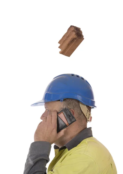 A brick falling from height towards a workers head which is protected by a safety helmet.