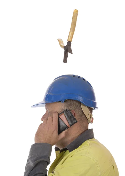 A tool falling from height towards a workers head which is protected by a safety helmet.