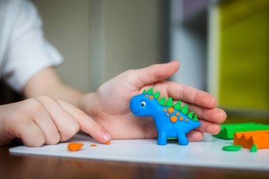 Yaratıcı çocuk evde kalıp. Çocuk oyun hamuru ile. Çocuk bir dinozor sculpts