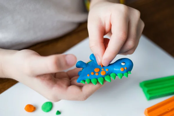 Yaratıcı çocuk evde kalıp. Çocuk oyun hamuru ile. Çocuk bir dinozor sculpts