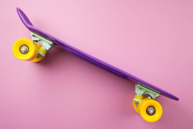 Mor gençlik kaykay pembe bir arka plan üzerinde. Çocuk plastik mini Kruvazör kurulu. kavram: sağlıklı yaşam, spor, hareket. Minimalizm, düz yatıyordu, kopya alanı
