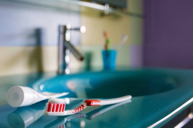 Diş Sağlığı: fırça ve diş macunu mavi lavabo banyo. iç su musluk arka plan üzerinde kırmızı diş fırçası yatıyor.