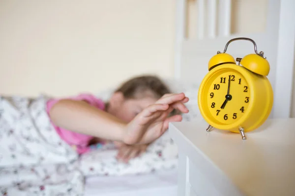 Okul çocuk yatakta uyur. Sarı alarm saat komidin yatağın arka planda ve oda iç uyuyan çocuk.