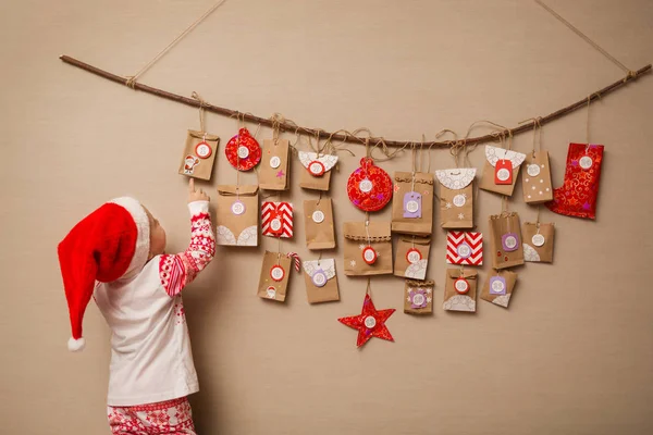 Ребенок Смотрит Календарь Пришествия Девочка Рождественской Шляпе Пижаме Первом Подарке — стоковое фото