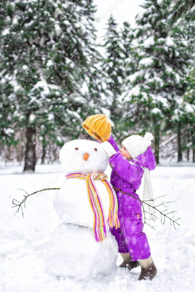 child sculpts a snowman in a snow-covered Park. winter outdoor activities.