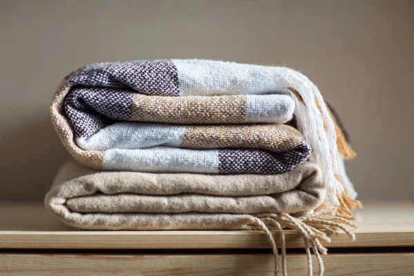 home textile. stack of beige wool blankets on a wooden shelf. autumn - winter concept of home warmth and comfort.