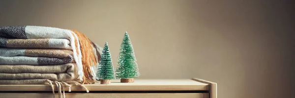 bej renkli damalı yün battaniye ve iki Noel ağacı ahşap göğüs yığını. Sıcacık kış natürmort. Ev tekstili. Uzun banner, kopya alanı