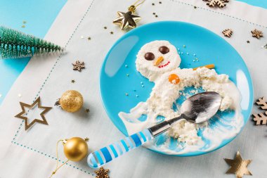 Çocuklar için eğlenceli yemek fikri. Noel çocuk kahvaltı: süzme peynir mavi tabakta kardan adam