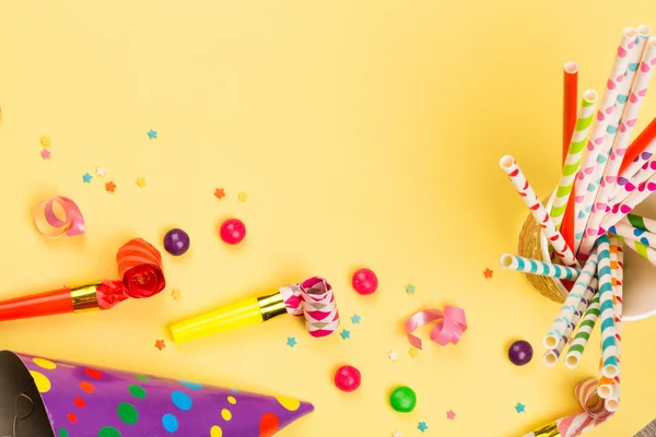 明亮的生日派对背景与鸡尾酒管 喇叭和糖果 五颜六色的假日配件在黄色的桌子上 顶视图 — 图库照片