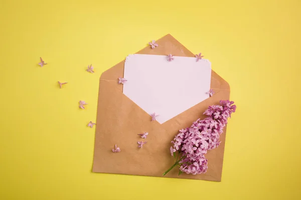 branch of purple lilac and the envelope with the letter on a yellow background. minimalism.