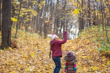 mutlu küçük çocuklar gülerek ve doğada sonbaharda yaprakları oynarken açık havada yürümek. yaşam tarzı