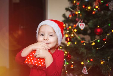 Noel ağacının arka planında yeteneği olan bir çocuk. Mutlu kız sarılır ve sarılır.