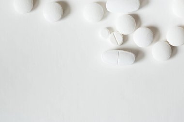 Beyaz zemin üzerinde çeşitli şekillerde tabletler üst görünümü kapatın. Minimalist ilaç ve tedavi kavramı.