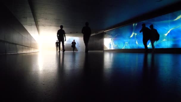 在蓝色照明的玻璃墙前走过的难以辨认的民族的慢动作剪影 行人地下通道 — 图库视频影像