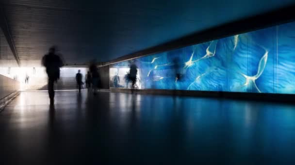 在蓝色照明的玻璃墙前走过的无法辨认的人们的剪影的延时 行人地下通道 — 图库视频影像