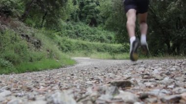 Ormanda spor yapan bir adam yolda koşuyor.