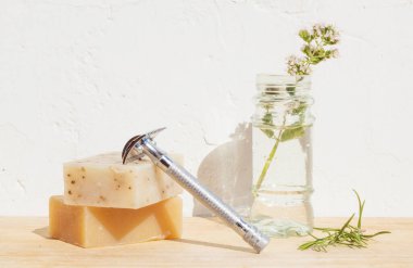 Çelik traş bıçağı, sabun, çiçek, biberiye, beyaz arka planda.