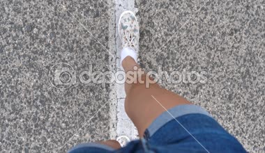 Kız asfalt yolda yürür. Ayak kızlar, asfalt, yol işaretleri, yaz aylarında İspanya dağ yolu.