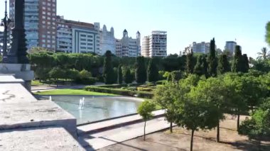 Valencia Park, köprü görünümü. Yeşil alan çiçek ve kaldırım döşeme. Küçük bir gölet ve arka planda konut kompleksleri.